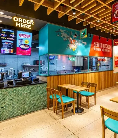 Interior view of a restaurant at Good Earth Business Bay I, Gurugram, showcasing sleek designs, digital ordering stations, and comfortable seating.