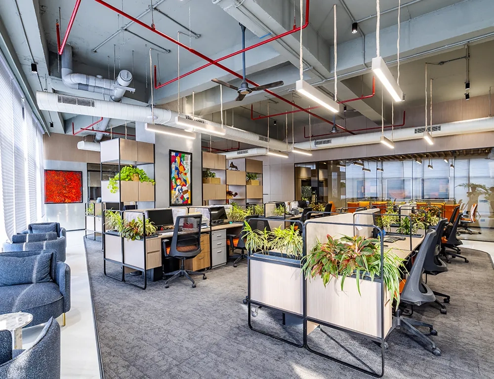 Bright and open workspace at Good Earth Infra, designed with ergonomic furniture and decorative plants for a corporate setting.